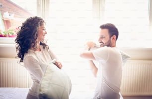 Young couple in bed playing and having fight with pillow. Space for copy. Close up.