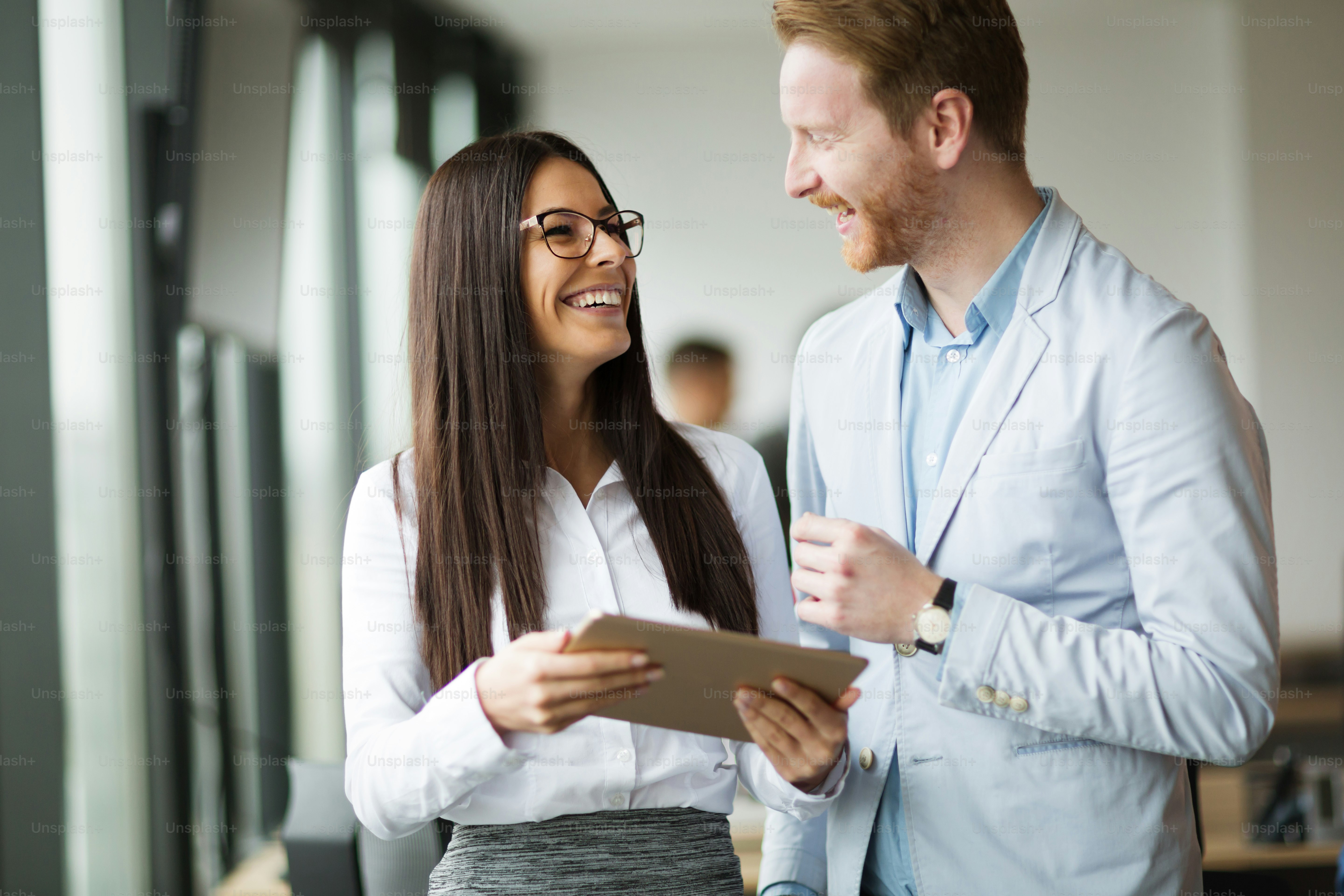 Businesspeople discussing while using digital tablet in office together