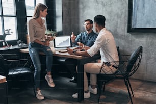 Group of young confident business people analyzing data using computer while working in the office