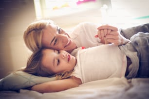 Portrait of happy mother and daughter lying on a bed.