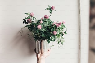 hand holding clover bouquet with pink flowers in metallic cane. wildflowers in rustic rural home. country slow living