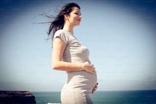 Mujer hermosa embarazada en la costa de la playa.