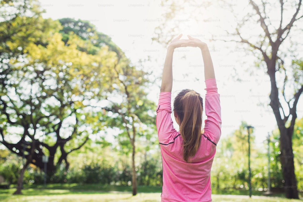 Asian young woman warm up the body stretching before morning exercise and yoga in the park under warm light morning. Healthy young asian woman exercising at park. Woman exercise outdoor concept.