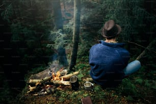 산속의 햇볕이 잘 드는 숲에서 캠핑하는 세련된 힙스터 여행자