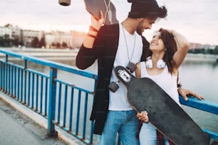 Picture of young attractive couple carrying skateboards and having fun