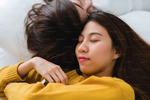 Belle giovani donne asiatiche LGBT lesbiche coppia felice che si abbracciano e sorridono mentre sono sdraiate insieme a letto sotto la coperta a casa. Donne divertenti dopo il risveglio. Coppia lesbica LGBT insieme al concetto di interni.