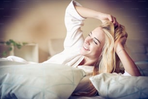 Donna sorridente che si sveglia a letto.