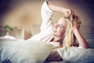 Mujer sonriente despertando en la cama.