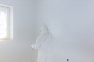 Trabajador pintando pared con Airless Spray Gun en color blanco.