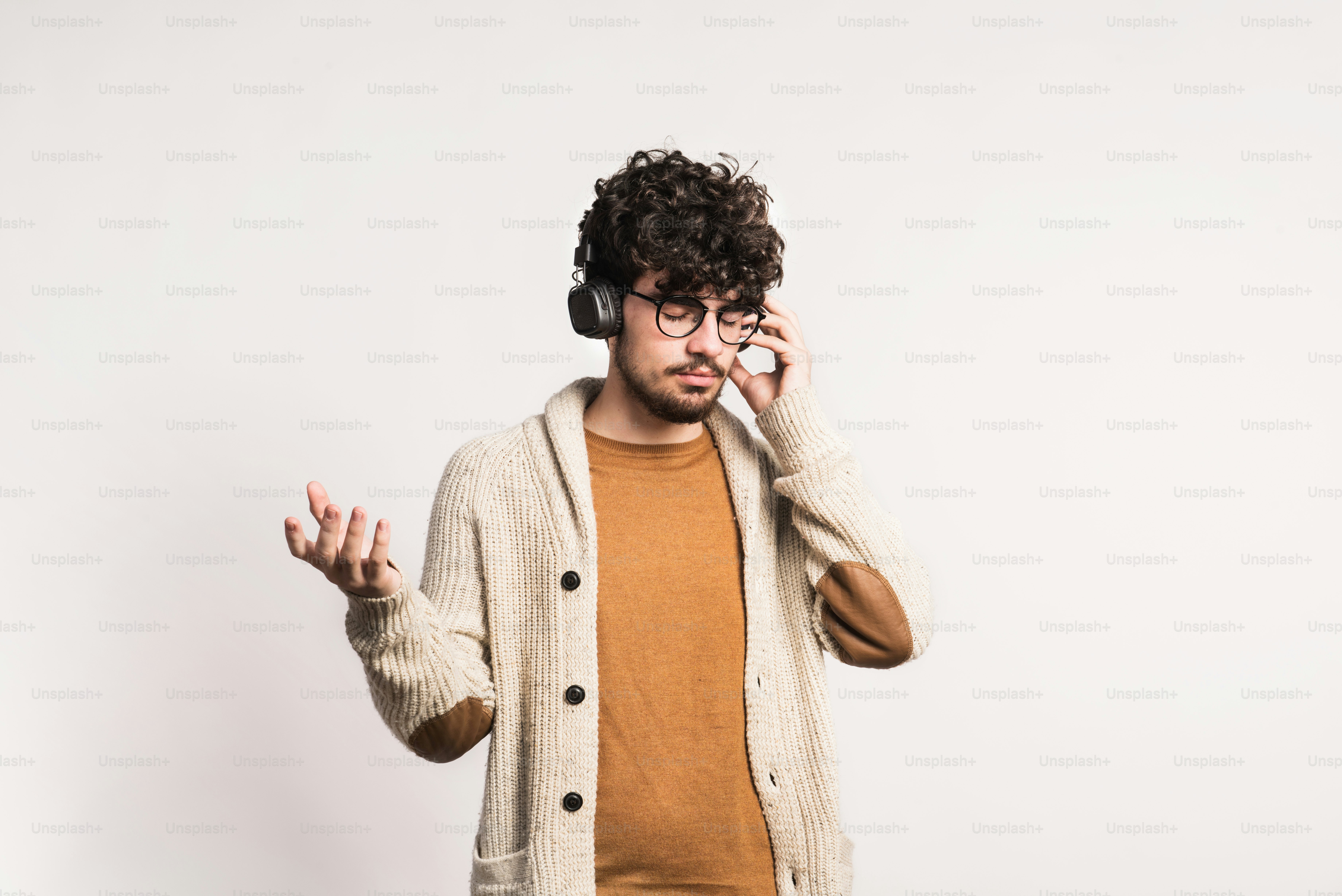 Um jovem bonito com fones de ouvido em um estúdio, ouvindo música.