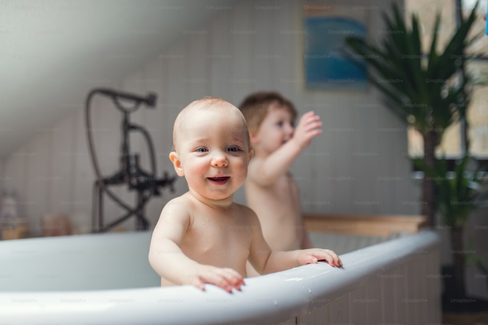 Dos niños pequeños felices bañándose en el baño de su casa.
