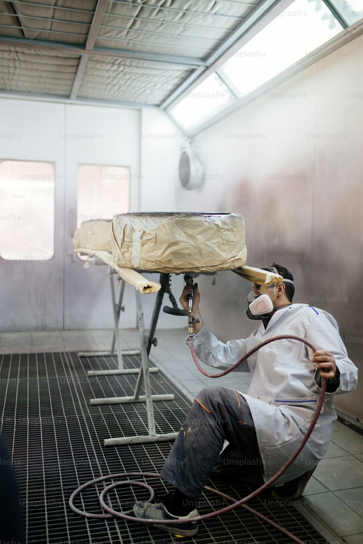 Professional paint spray booth operation showing industrial coating application with proper ventilation and safety equipment