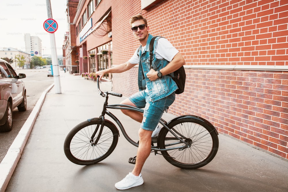 Guapo hipster disfrutando de un paseo por la ciudad en bicicleta