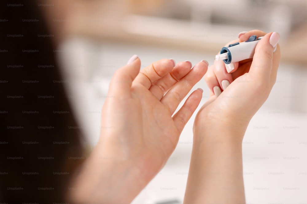 Rapid test. Close up of beautiful female hands applying glucometer while monitoring blood sugar level