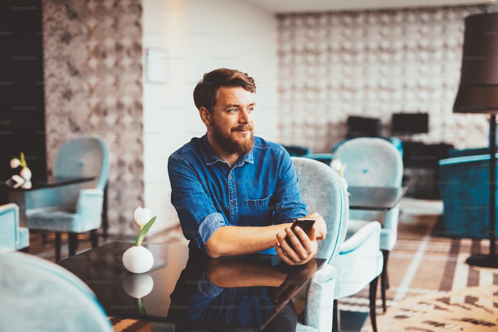 Man waiting for woman in restaurant and checking phone