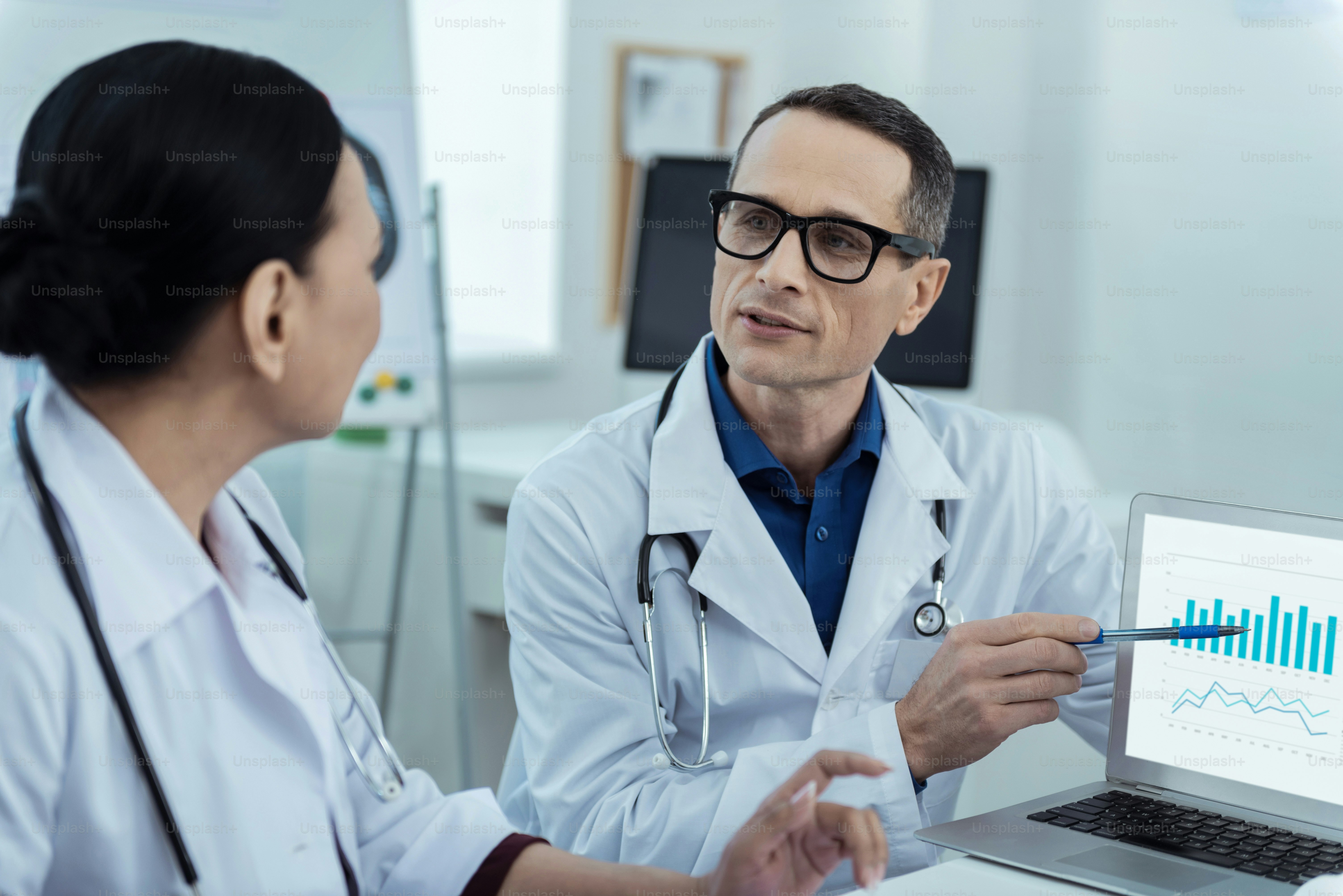 Data analysis. Professiaonl pleasant doctors discussing the statistics while sitting at the table