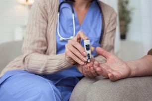 Blood sugar. Close up of female tender hands using blood glucose meter while taking blood sample