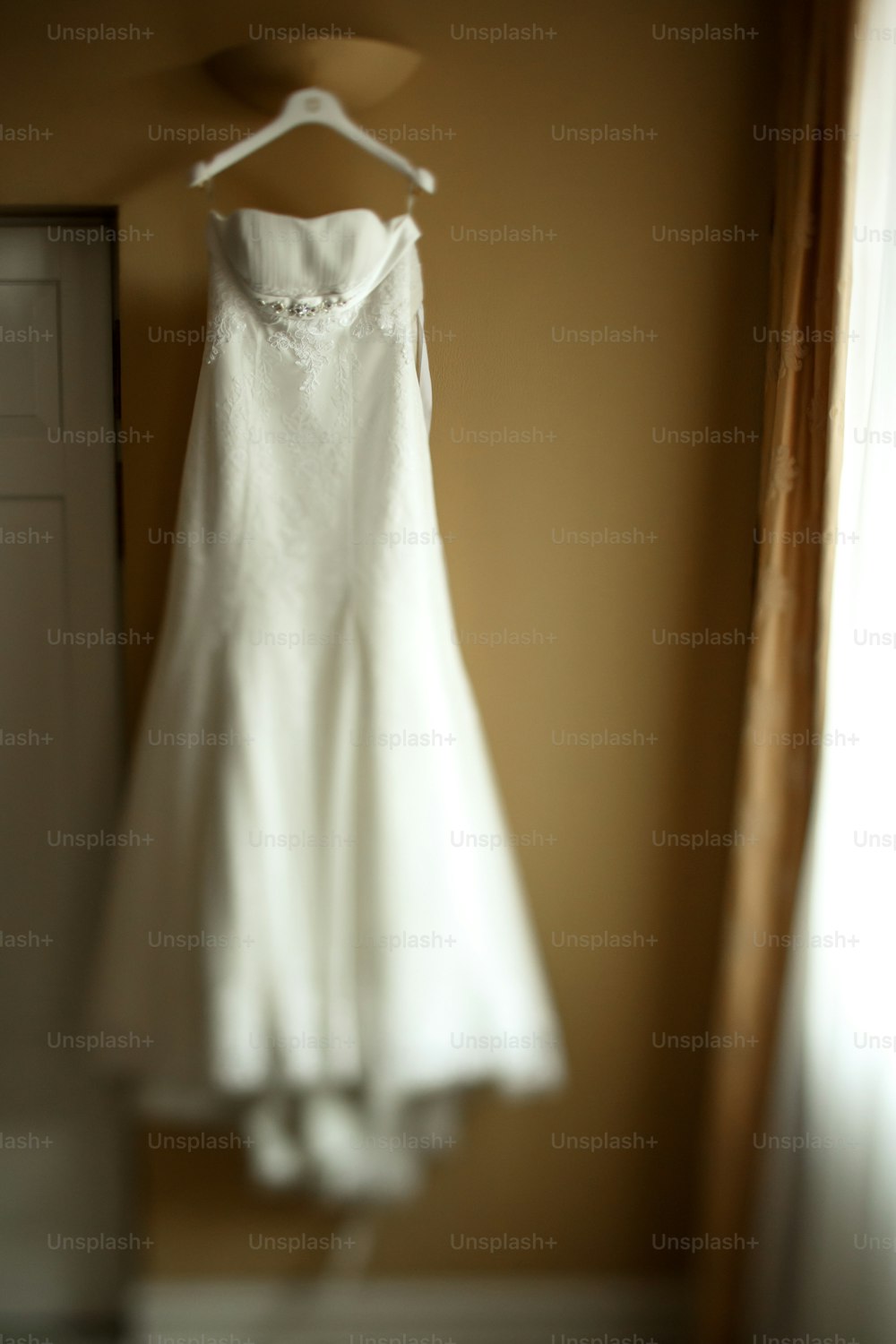 luxury wedding dress hanging in room in the morning