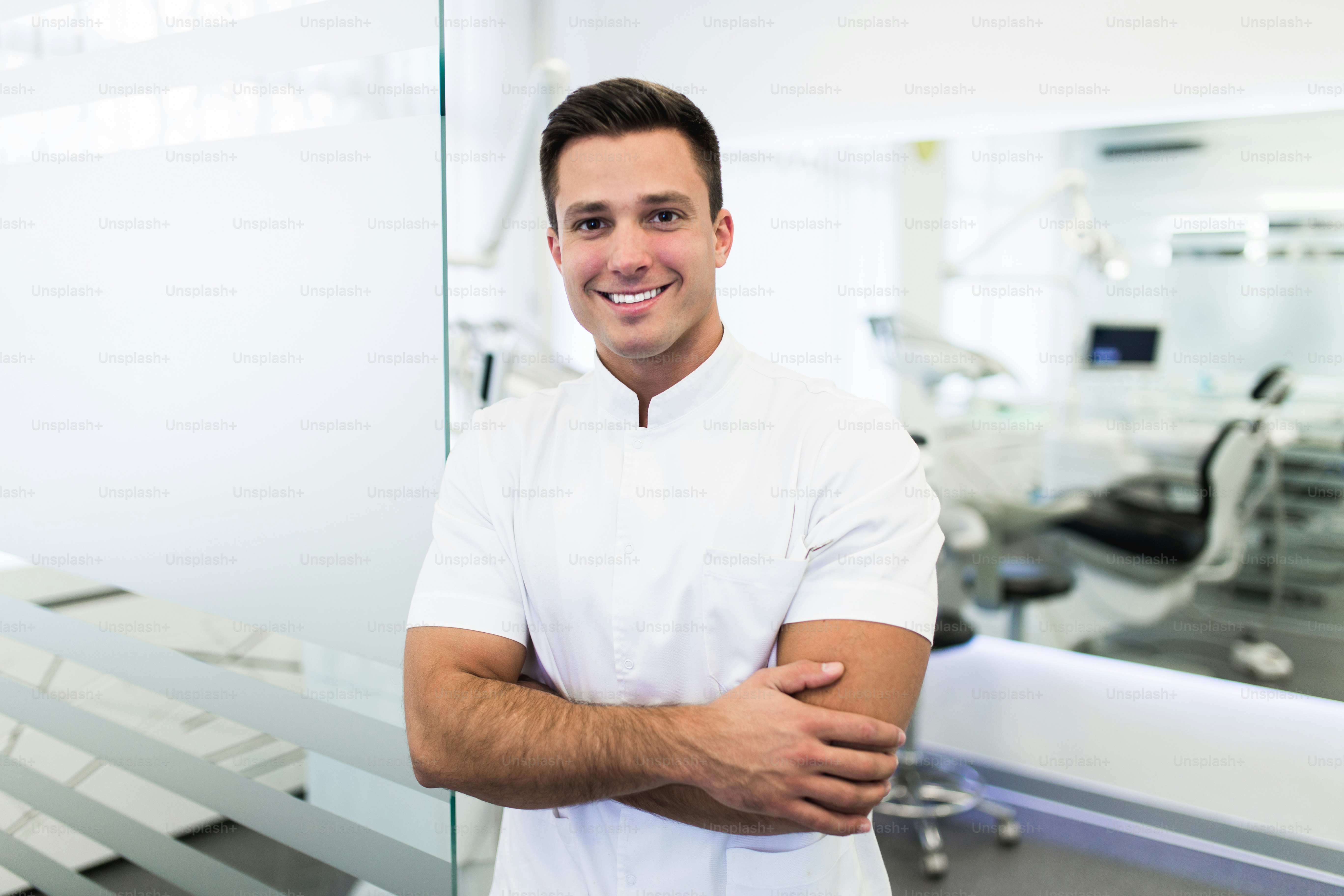 Handsome male dentist in doctors white lab coat posing in modern dental ...