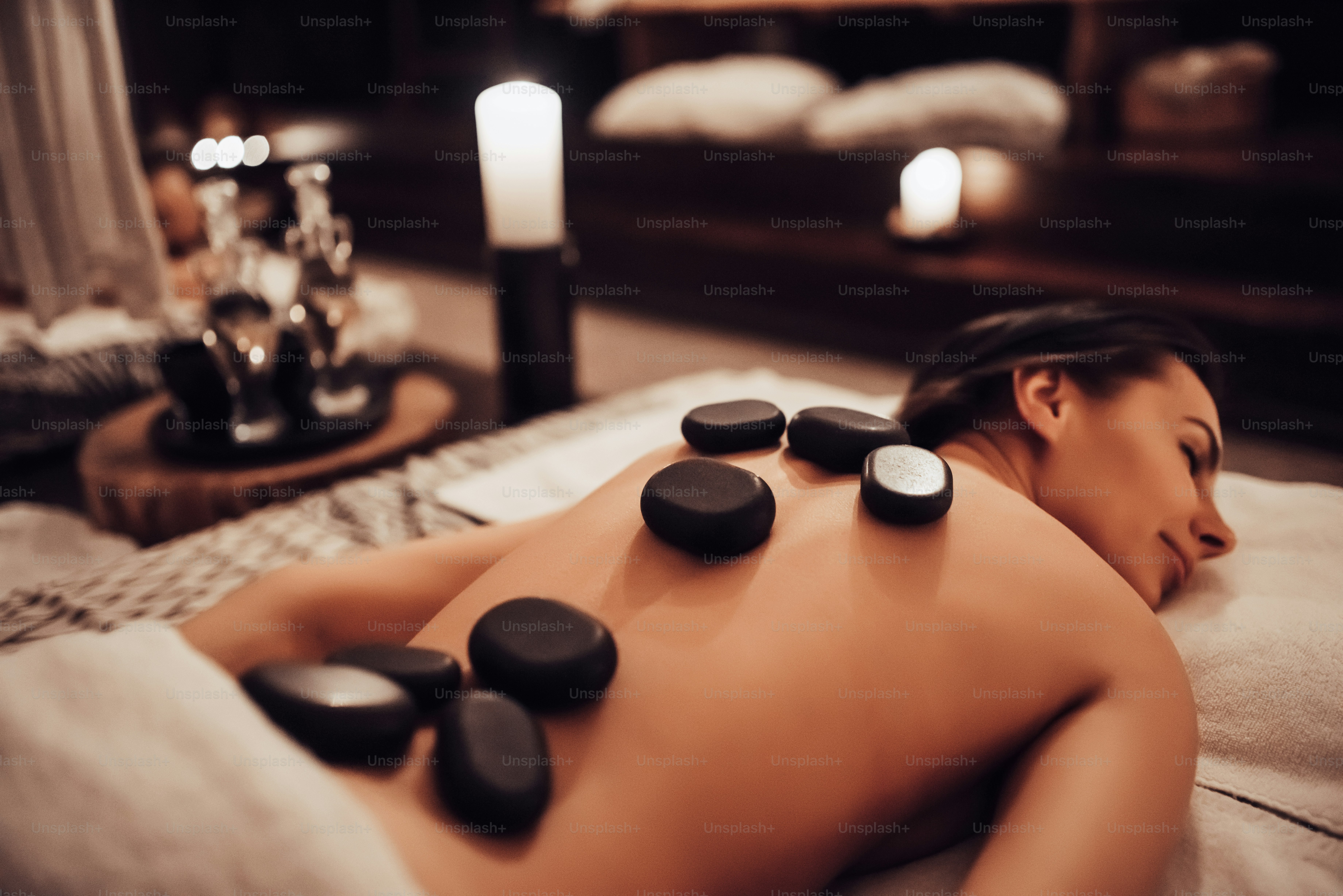Dua wanita muda sedang bersantai di spa dan pusat kesehatan sambil menerima pijat batu. Konsep perawatan kecantikan.