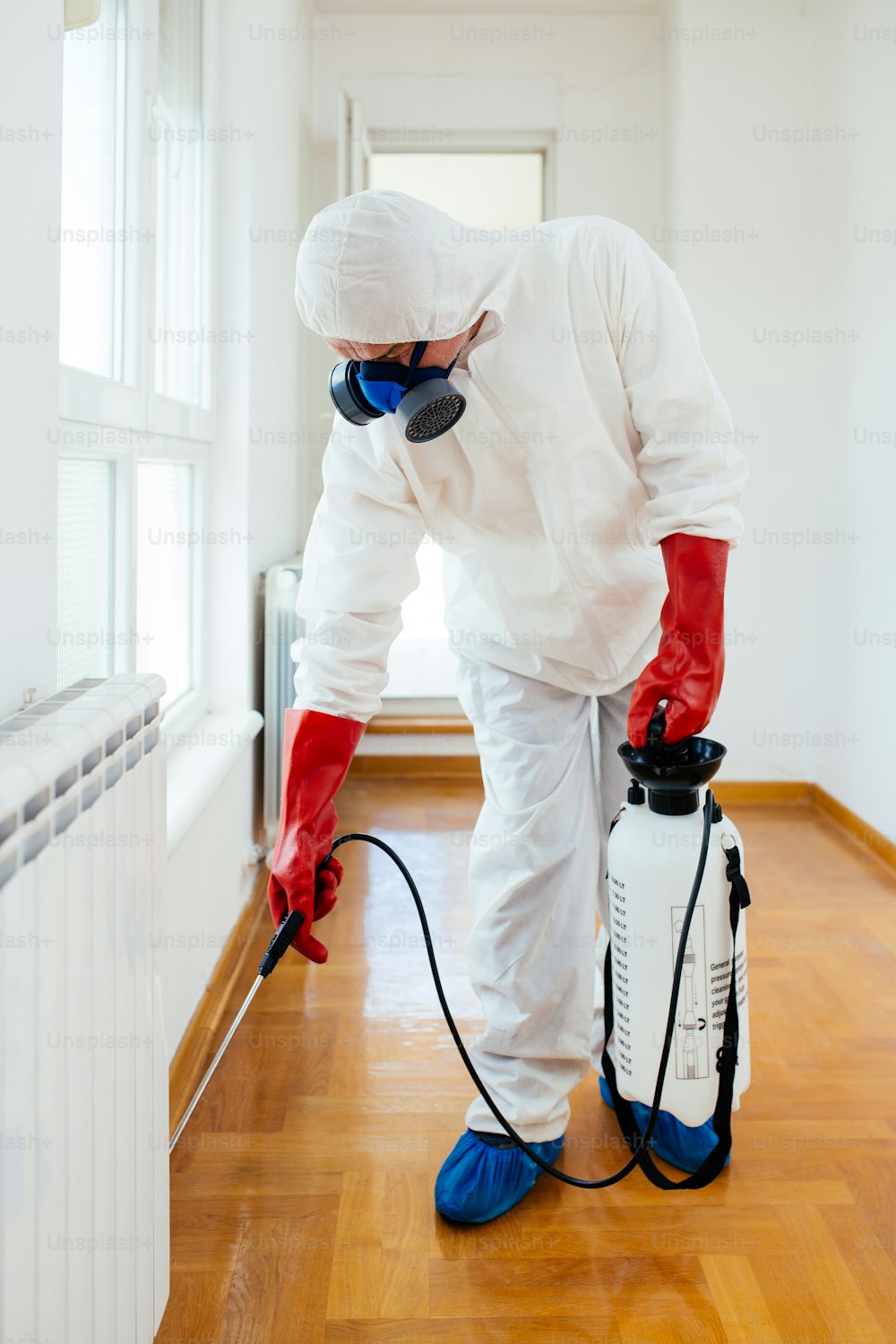 Exterminador en ropa de trabajo rociando pesticida o insecticida con rociador