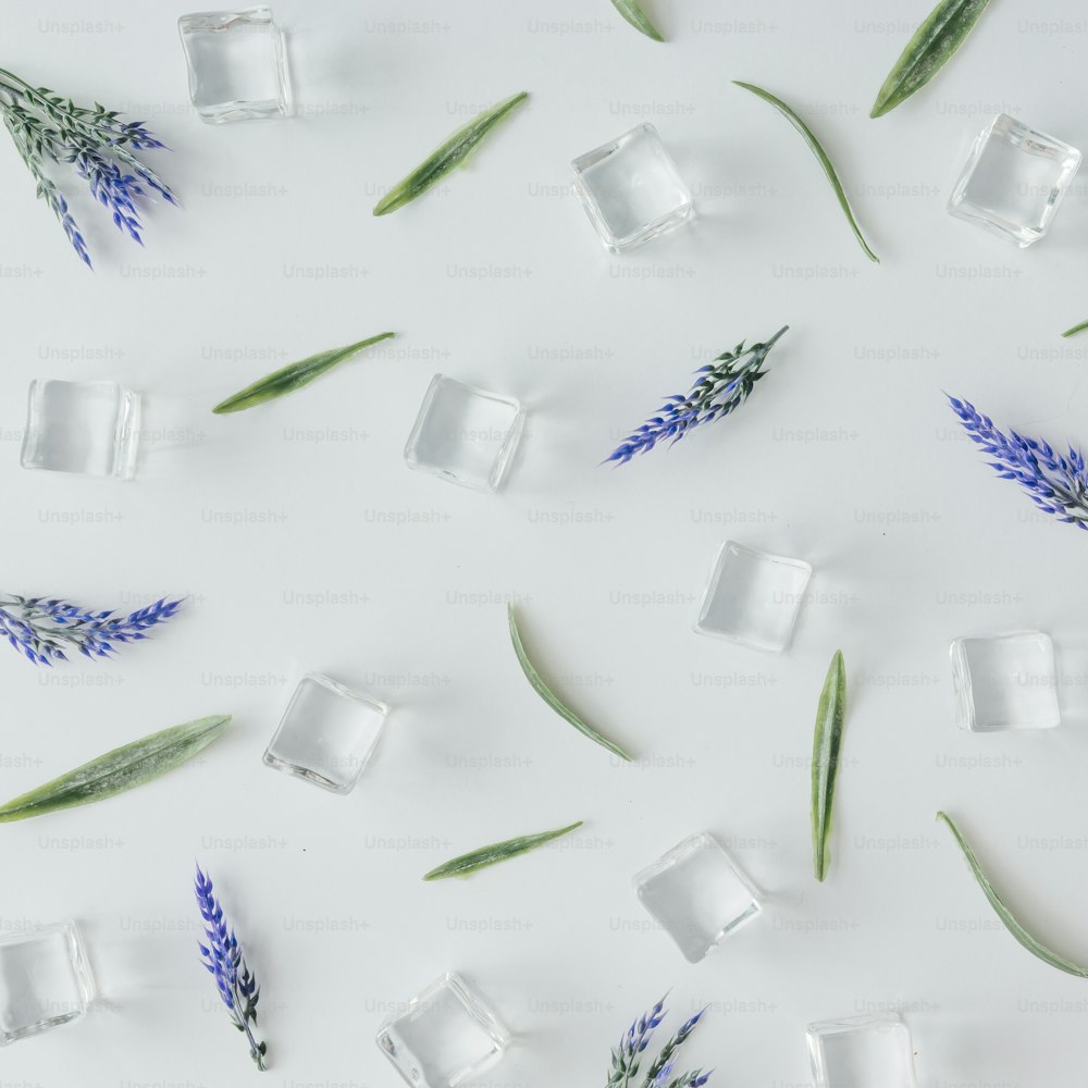 Creative pattern of ice cubes , leaves and flowers on bright background. Flat lay summer drink minimal concept.