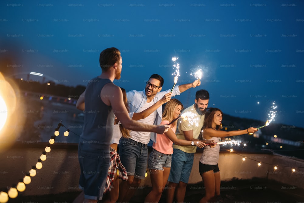 Group of friends enjoying rooftop party with sparklers