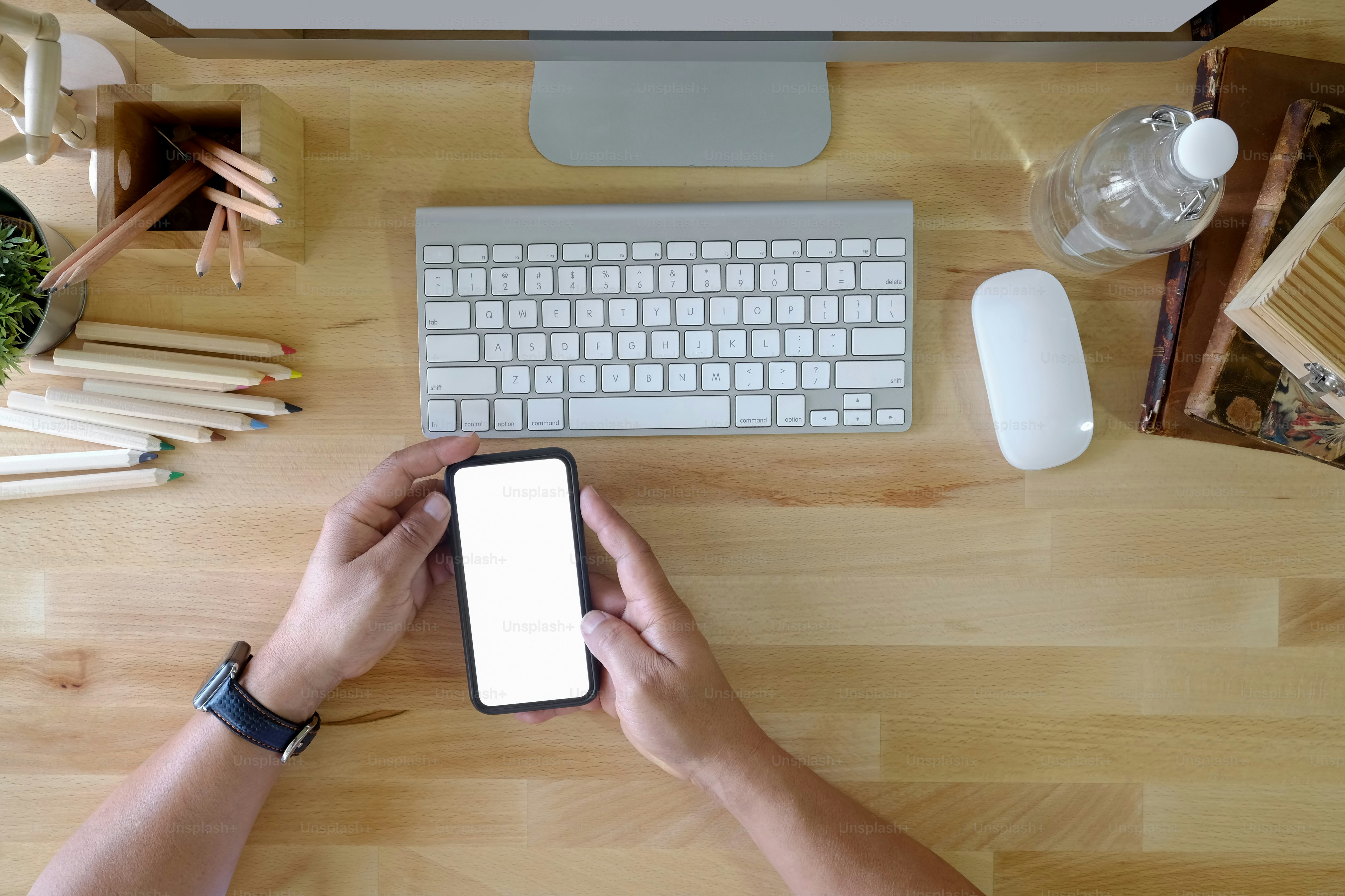 Man hand holding blank screen mobile phone on wooden office table.