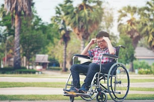 Alone boy in wheelchair having an headache at park