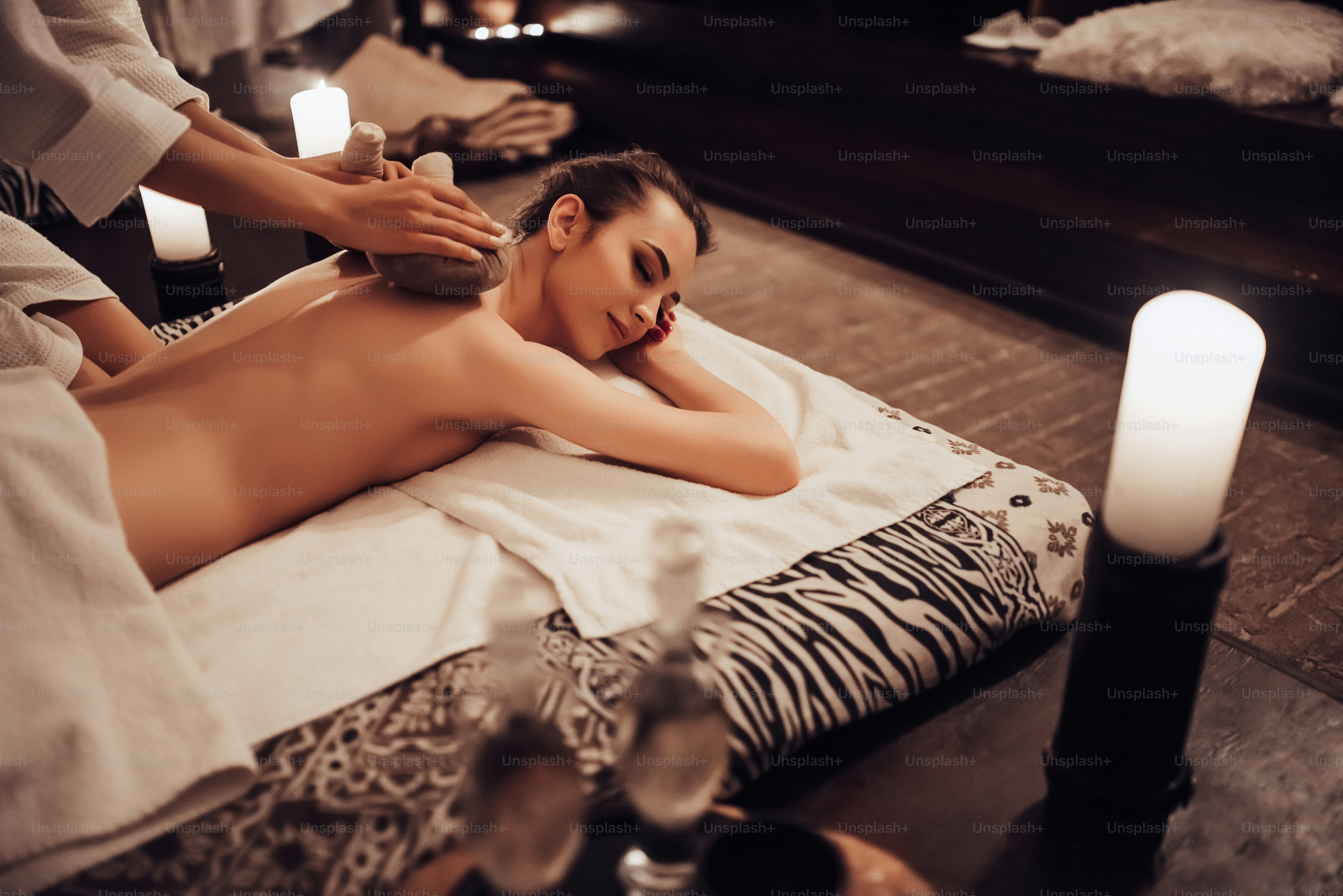 Attractive young woman is relaxing in spa and wellness center while receiving body massage. Beauty treatment concept.