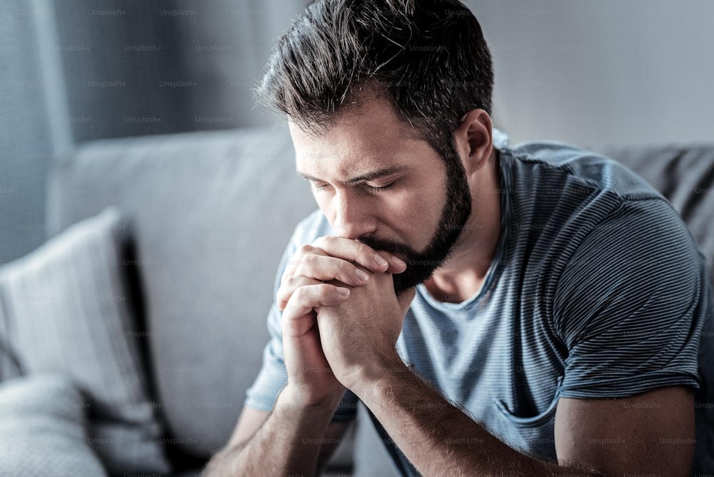 Cosa fare. Uomo infelice serio e spensierato che si tiene il mento e guarda in basso mentre pensa a cosa fare per il suo problema