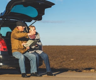 Happy senior couple on a road trip, they are using map for direction.