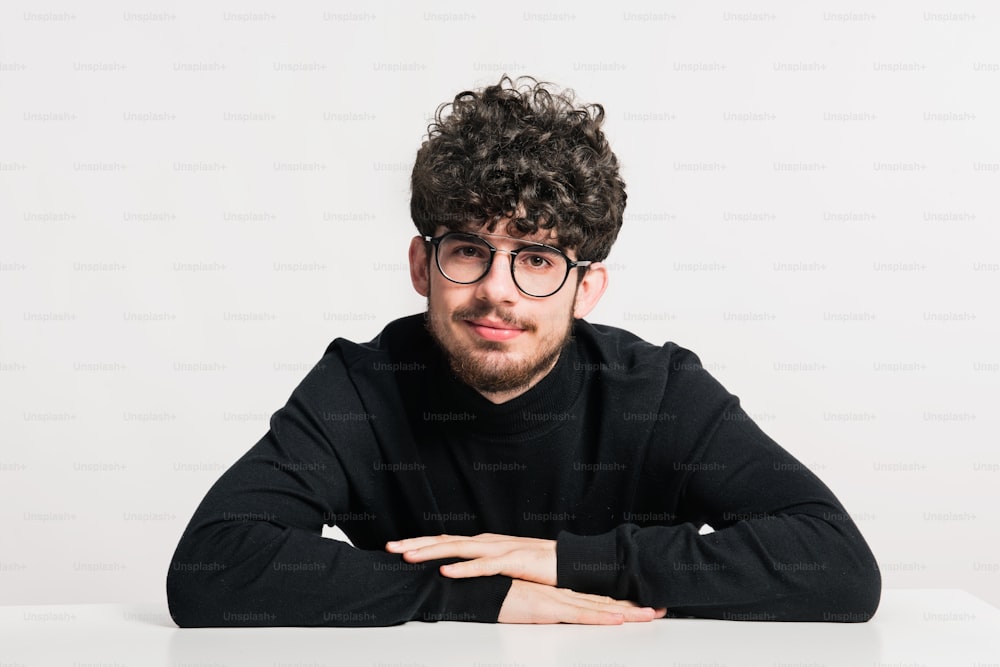 Portrait of a young man in a studio, sitting at a table.