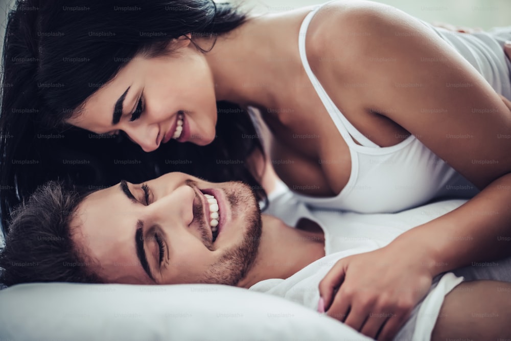 Una pareja feliz está acostada en la cama juntos. Disfrutar de la compañía de los demás.