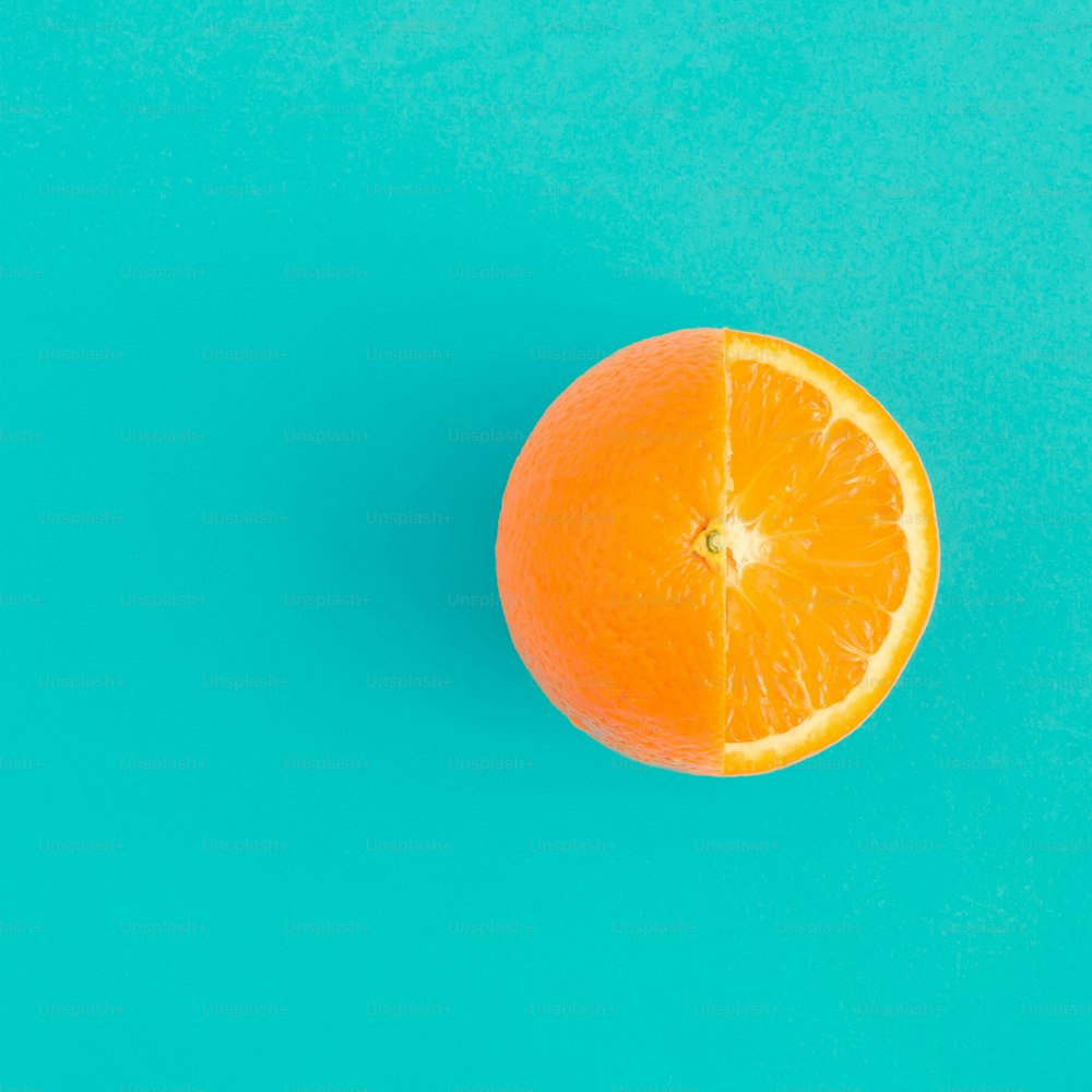 明るい青色の背景にオレンジ色の果物。ミニマルフラットレイのコンセプト。