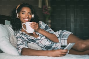 Donna sul letto che ascolta musica con cuffie e smartphone