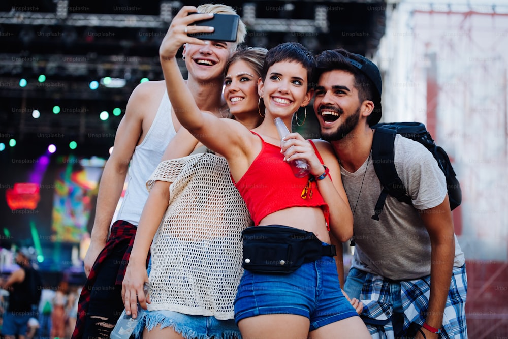Giovani amici felici che scattano selfie al festival musicale