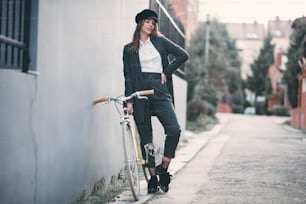 Femme debout dans la rue à côté de son vélo fixie.