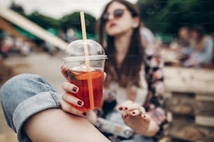 strawberry lemonade in hand. stylish hipster woman in sunglasses with red lips holding lemonade. cool boho girl with cocktail at street food festival. summertime. summer vacation travel