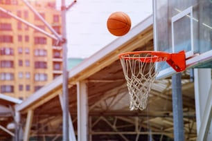 Action shot of basketball falls through basketball hoop and net on park background