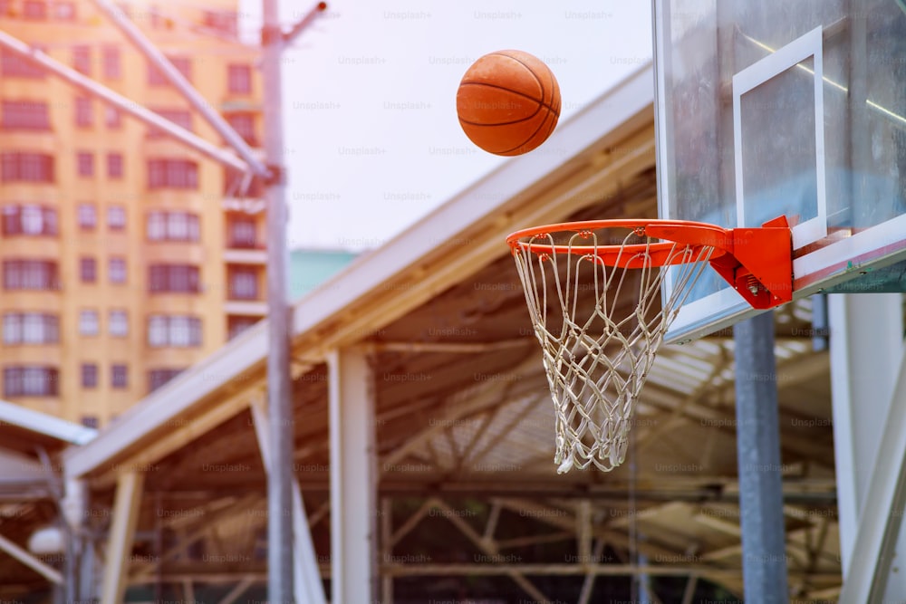 Action shot of basketball falls through basketball hoop and net on park background