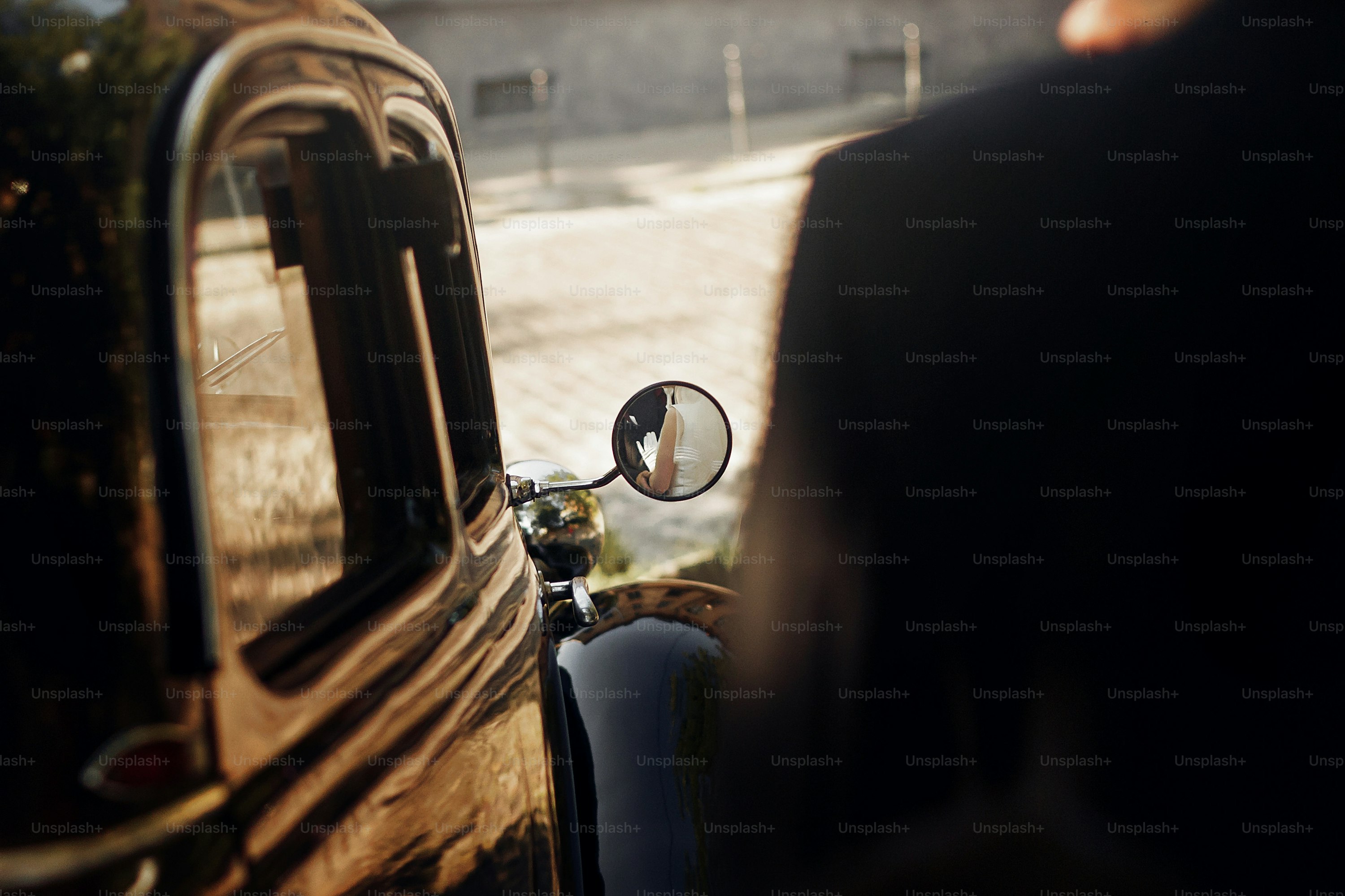 Vista inusual en la pareja de bodas elegante de lujo que se abraza, reflejo en el espejo de las manos en el elegante coche negro. Estilo retro. Momento romántico