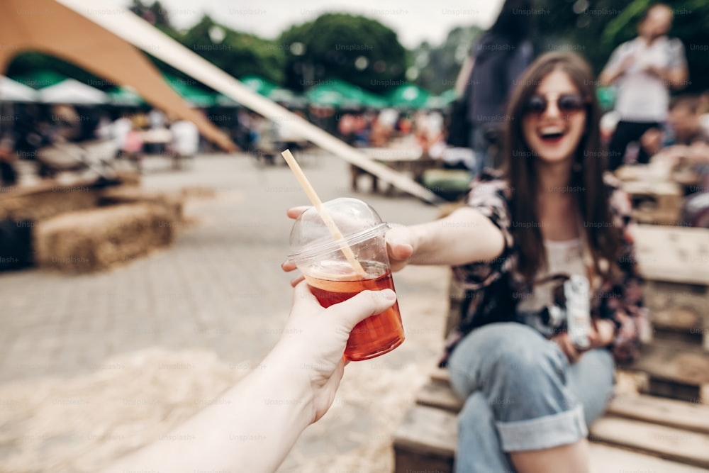 lemonade in hand. man giving lemonade to stylish hipster woman in sunglasses with red lips. cool boho girl with cocktail at street food festival. summer vacation, space for text