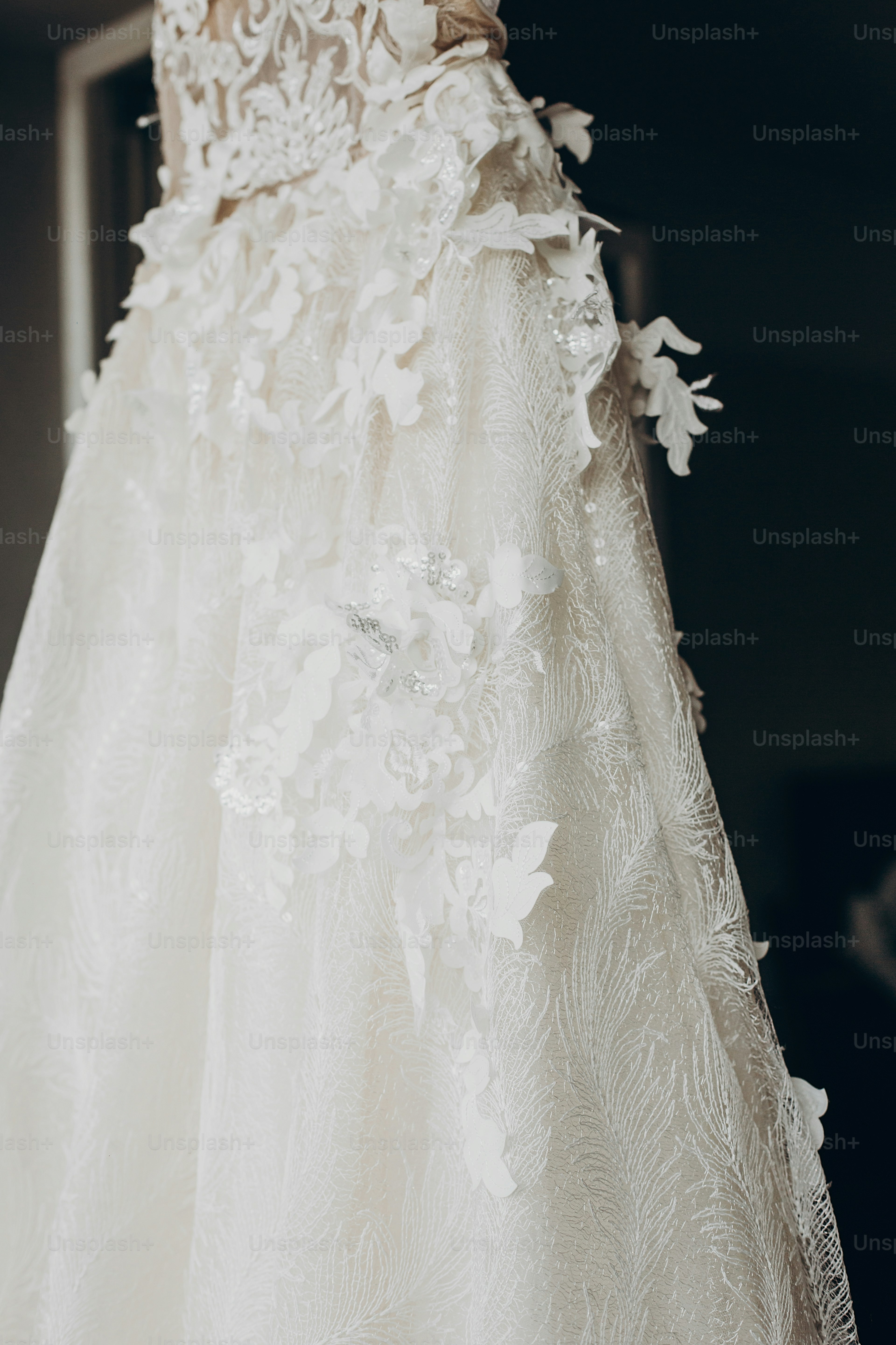 Detalle del vestido de novia de lujo, colgado en la ventana de una habitación de hotel. Vestido de novia moderno y sorprendente con flores de cerca en la luz. Preparación matutina, preparándose. espacio para el texto . El día de la boda