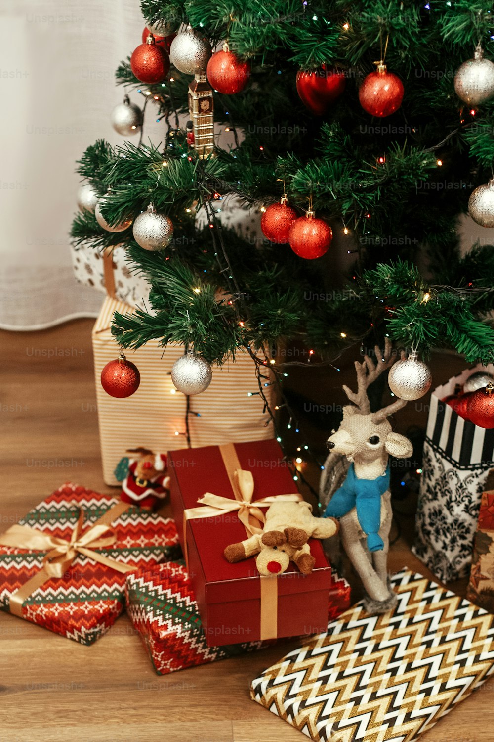 Regali di Natale di lusso giocattoli in carta da regalo moderna. Eleganti regali dorati sotto il bellissimo albero di Natale in camera. concetto di saluti stagionali. spazio per il testo. Babbo Natale