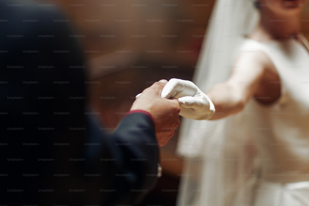 ゴージャスな花嫁の手を優しく握るエレガントでスタイリッシュな新郎の接写。レトロなスタイルの珍しい豪華な結婚式のカップル。ロマンチックなひととき