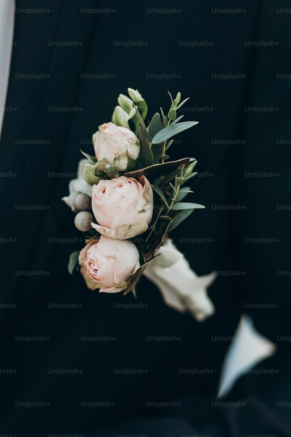 luxury boutonniere with roses on groom stylish suit. space for text. sunny wedding day. pink flowers and green leaves on tuxedo chest. modern look, close-up