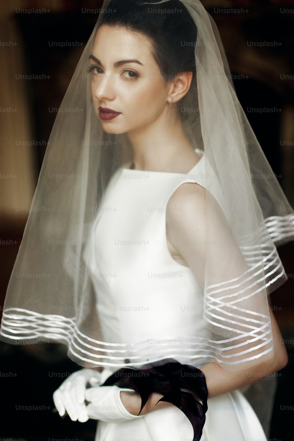 elegant gorgeous bride holding calla bouquet, posing under veil. sensual look. unusual luxury wedding in retro style.