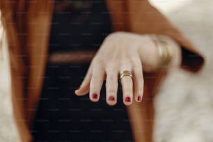 반지를 가진 손을 보여주는 세련된 보헤미안 여자. 현대적인 청동 액세서리를 착용한 프린지 재킷을 입은 집시 힙스터 소녀. 방랑벽 여름 여행. 대기 순간.