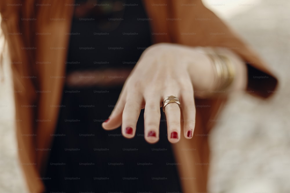 Stilvolle Boho-Frau, die Hand mit Ringen zeigt. Zigeuner-Hipster-Mädchen in Fransenjacke mit modernem Accessoire aus Bronze. Fernweh Sommerreisen. atmosphärischer Moment.